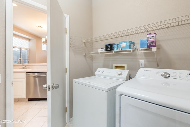 clothes washing area with laundry area, independent washer and dryer, a sink, and light tile patterned flooring