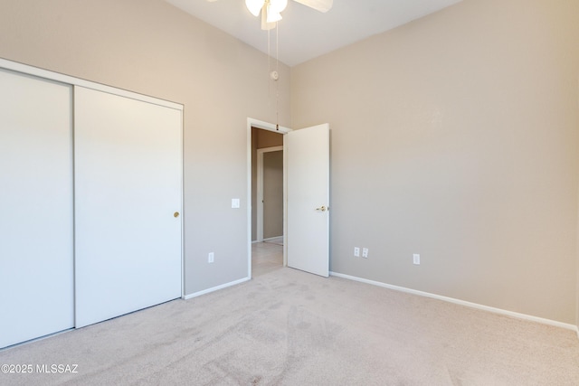 unfurnished bedroom with a closet, carpet, a towering ceiling, and baseboards