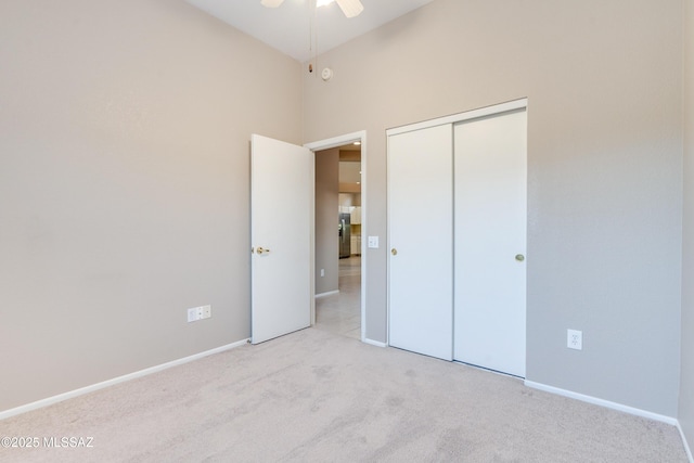 unfurnished bedroom with a closet, carpet, stainless steel fridge, and baseboards