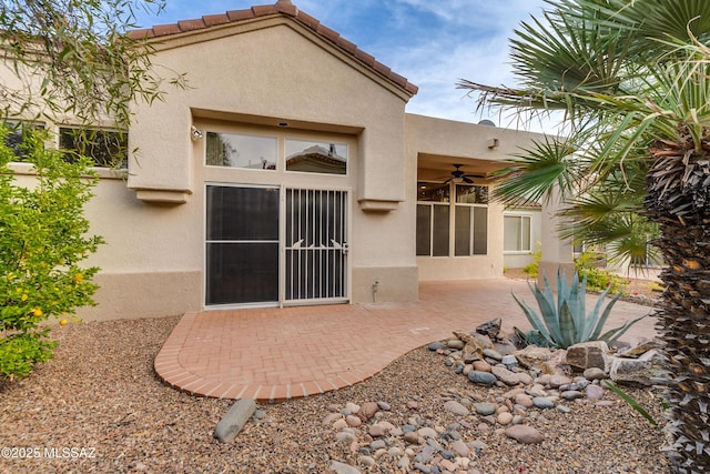 rear view of property featuring a patio area, a tile roof, and stucco siding