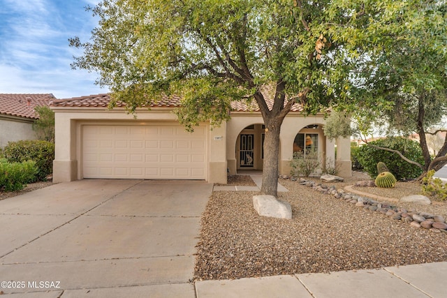 view of front of home featuring a garage, driveway, a tiled roof, and stucco siding