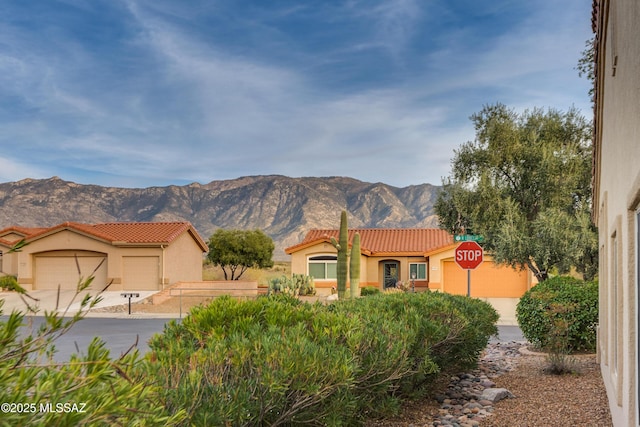 mediterranean / spanish home featuring a garage, a tile roof, a mountain view, and stucco siding