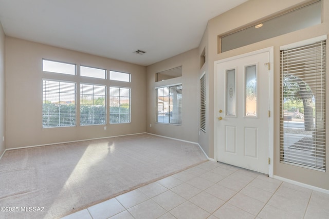 entryway with light carpet, baseboards, and light tile patterned floors