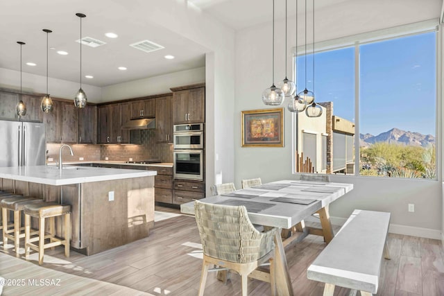 kitchen with under cabinet range hood, visible vents, appliances with stainless steel finishes, and light countertops