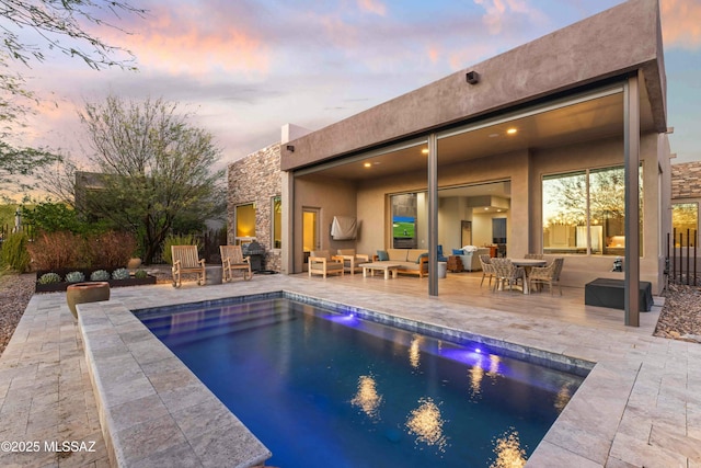 pool at dusk featuring a patio area, outdoor lounge area, and a fenced in pool