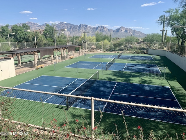 view of tennis court featuring fence and a mountain view