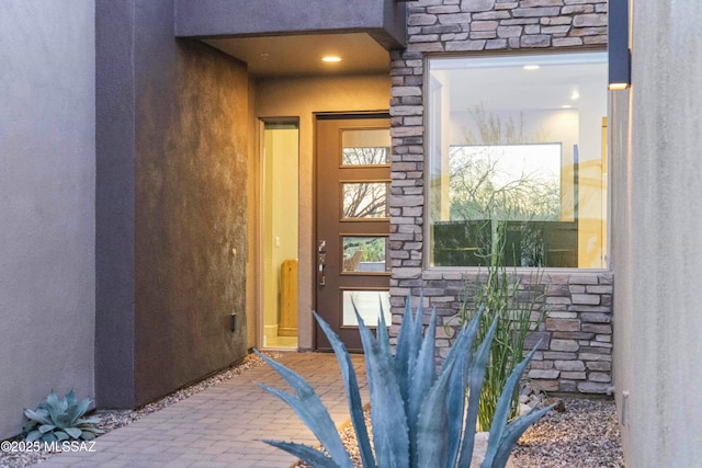 doorway to property featuring stone siding and stucco siding