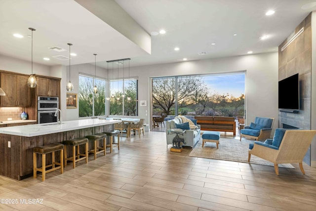 living area featuring recessed lighting, visible vents, plenty of natural light, and light wood-style flooring