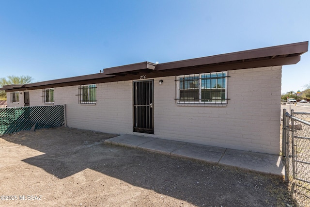 back of property featuring brick siding and fence