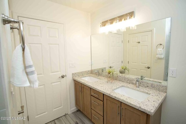 full bath featuring double vanity, wood finished floors, a sink, and toilet