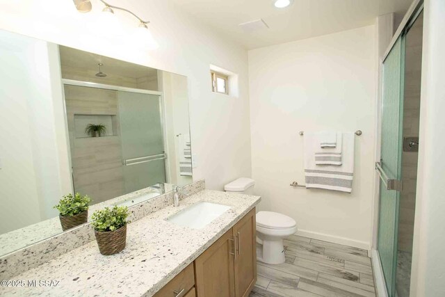 full bath with vanity, wood finished floors, a shower stall, and toilet