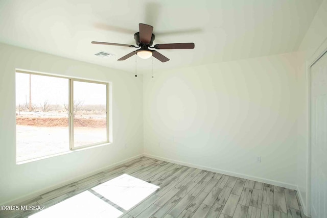 empty room featuring ceiling fan, light wood-type flooring, visible vents, and baseboards