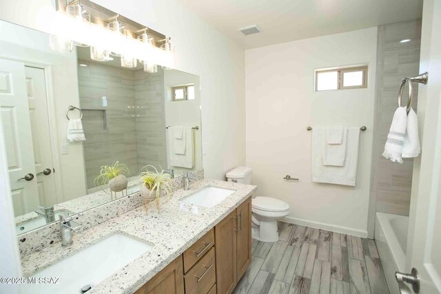 bathroom with toilet, a shower, a sink, and visible vents