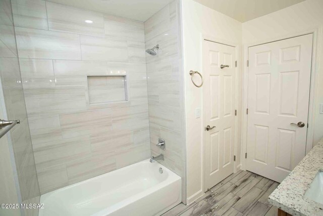 full bath with tub / shower combination, a sink, a walk in closet, and wood tiled floor