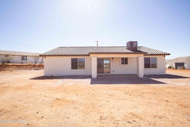 rear view of house featuring cooling unit, a tile roof, and stucco siding