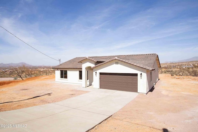 mediterranean / spanish home with driveway, an attached garage, a tile roof, and stucco siding