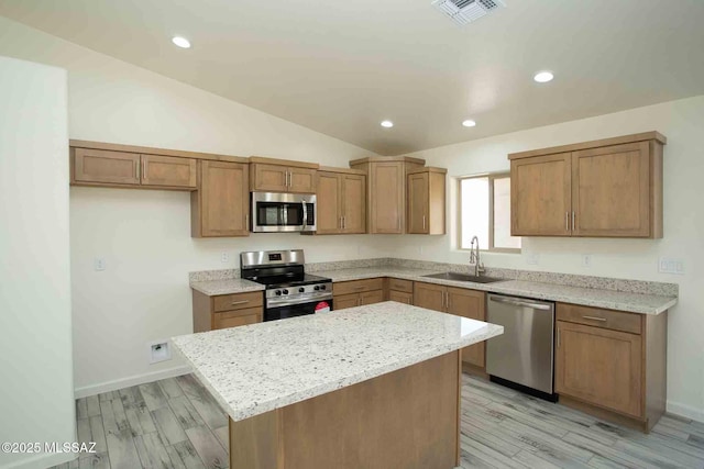 kitchen featuring visible vents, a kitchen island, vaulted ceiling, stainless steel appliances, and a sink