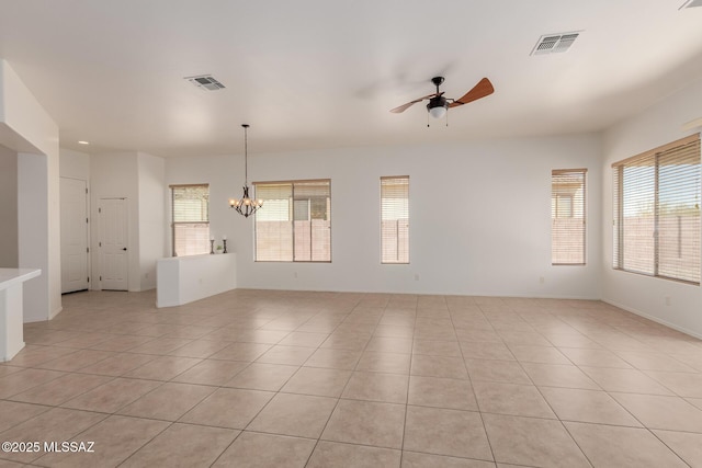 spare room with light tile patterned flooring, visible vents, and ceiling fan with notable chandelier