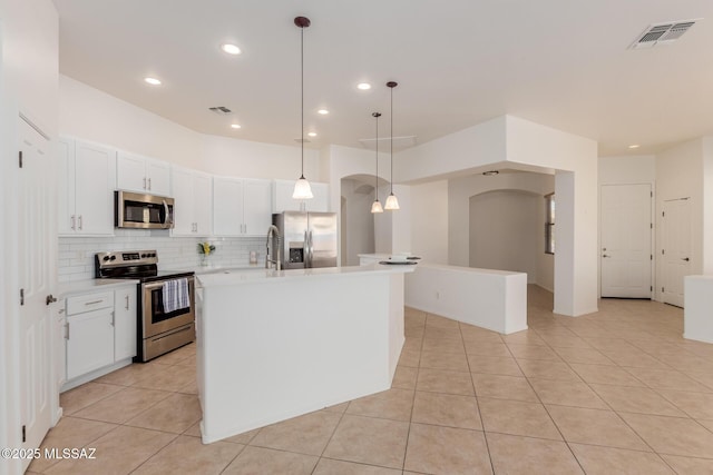kitchen with visible vents, arched walkways, decorative backsplash, appliances with stainless steel finishes, and light countertops