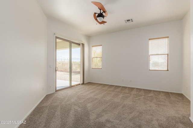 carpeted spare room featuring baseboards, visible vents, and a healthy amount of sunlight