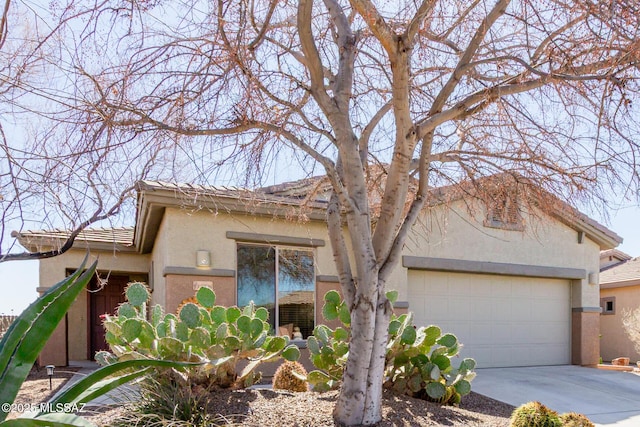 view of front of house with an attached garage, driveway, a tiled roof, and stucco siding