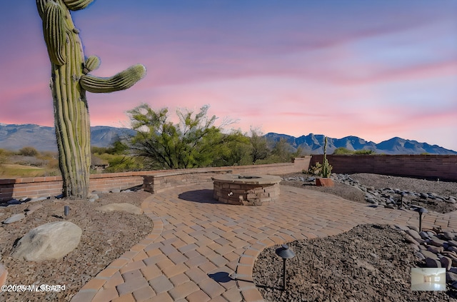 patio terrace at dusk featuring a mountain view and fence