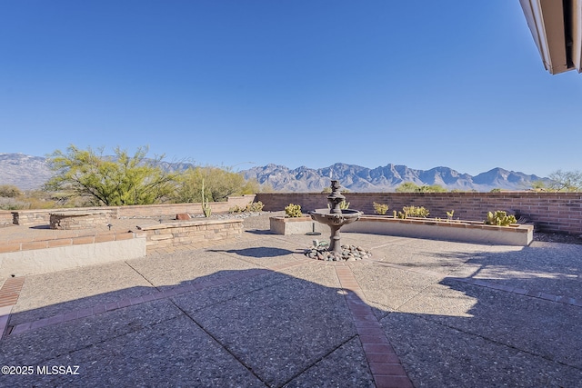 view of yard featuring a patio area, a mountain view, and a fenced backyard