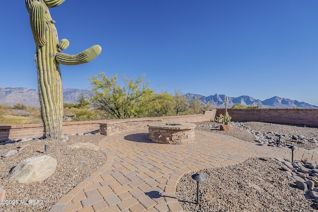 view of patio featuring an outdoor fire pit, a mountain view, and fence