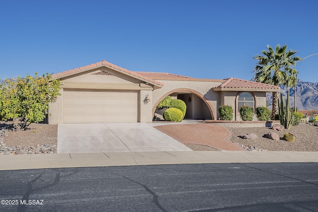 view of front facade with a garage, a tile roof, driveway, and stucco siding