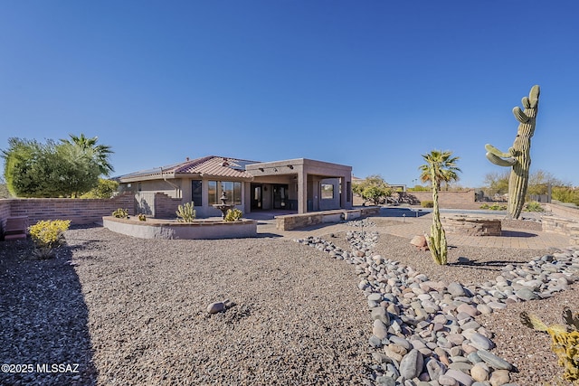 rear view of house with a tile roof, stucco siding, solar panels, a patio area, and fence