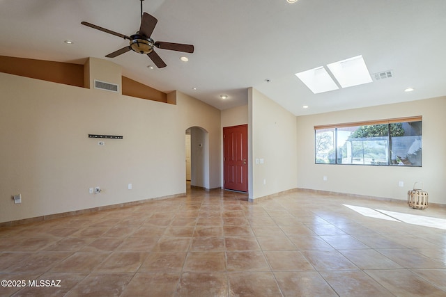 empty room with light tile patterned floors, arched walkways, visible vents, and recessed lighting