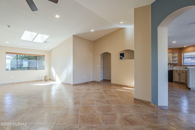 empty room with light tile patterned floors, recessed lighting, a sink, baseboards, and vaulted ceiling