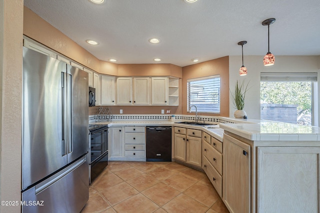 kitchen featuring light tile patterned floors, light brown cabinetry, a sink, a peninsula, and black appliances