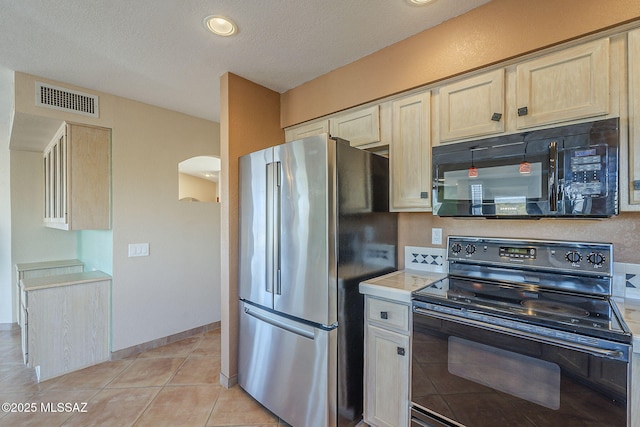 kitchen with light tile patterned floors, arched walkways, visible vents, light countertops, and black appliances