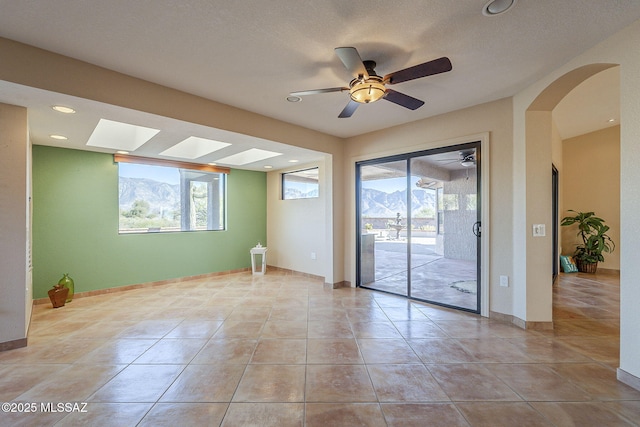 empty room featuring arched walkways, recessed lighting, tile patterned flooring, and baseboards