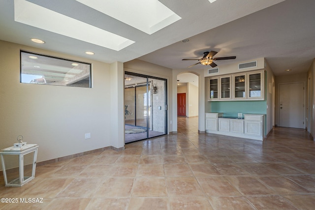 spare room featuring a skylight, visible vents, arched walkways, and a ceiling fan