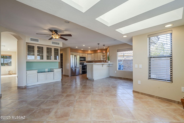 kitchen featuring freestanding refrigerator, black microwave, visible vents, and a peninsula