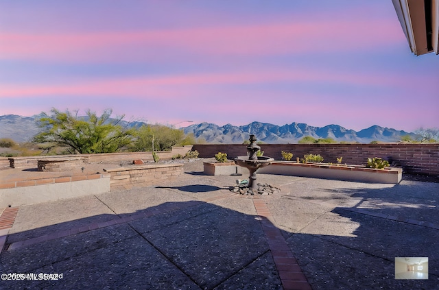 patio terrace at dusk featuring a fenced backyard and a mountain view