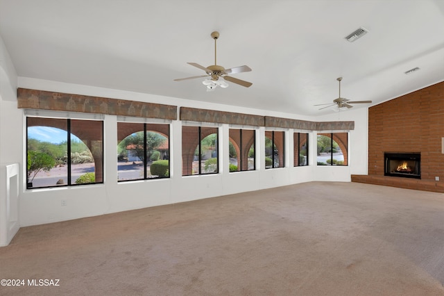 unfurnished living room with lofted ceiling, ceiling fan, a fireplace, carpet flooring, and visible vents