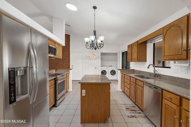 kitchen featuring lofted ceiling, appliances with stainless steel finishes, a center island, washing machine and dryer, and a sink