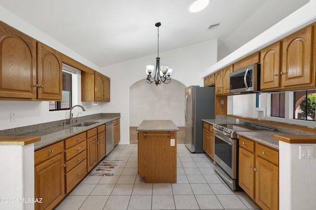 kitchen with lofted ceiling, stainless steel appliances, a sink, visible vents, and a center island