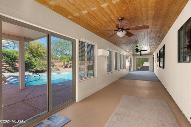 exterior space featuring a pool with connected hot tub, a wall unit AC, and a ceiling fan