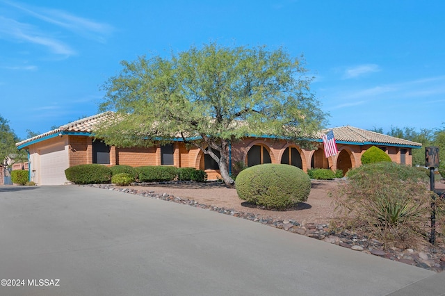 view of front of property featuring concrete driveway, a tiled roof, and an attached garage