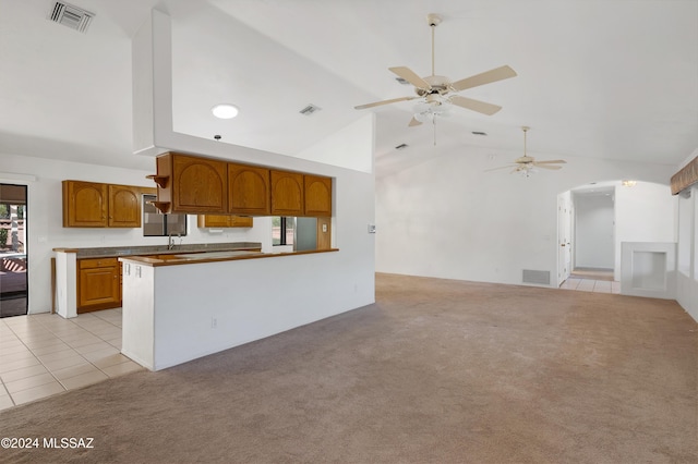 kitchen with vaulted ceiling, visible vents, brown cabinetry, and light colored carpet