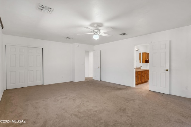 unfurnished bedroom with light colored carpet, a closet, visible vents, and a sink