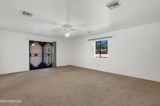 carpeted spare room featuring ceiling fan and visible vents