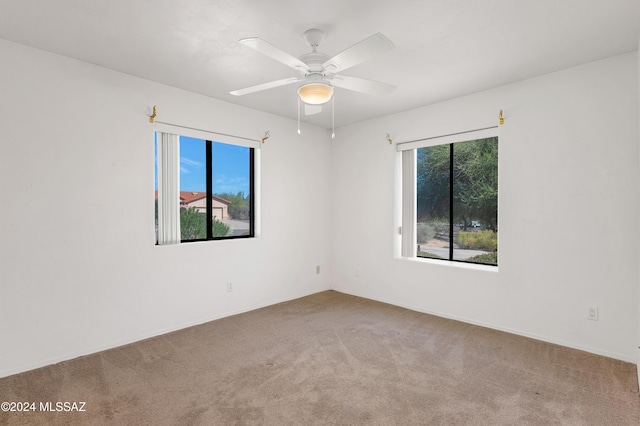 unfurnished room featuring a wealth of natural light, carpet, and ceiling fan