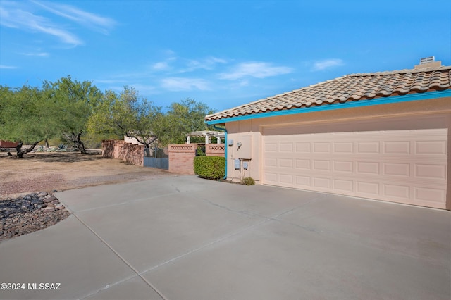 view of side of property featuring a garage, a tiled roof, and stucco siding