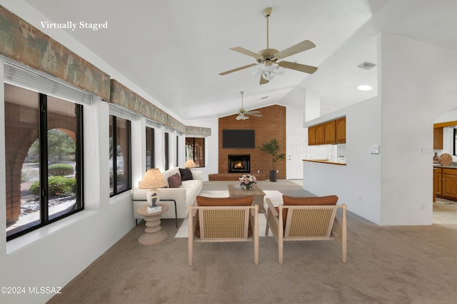 living room featuring light carpet, visible vents, a ceiling fan, vaulted ceiling, and a brick fireplace