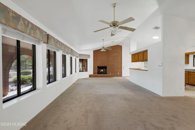 unfurnished living room featuring a fireplace, lofted ceiling, visible vents, light carpet, and ceiling fan